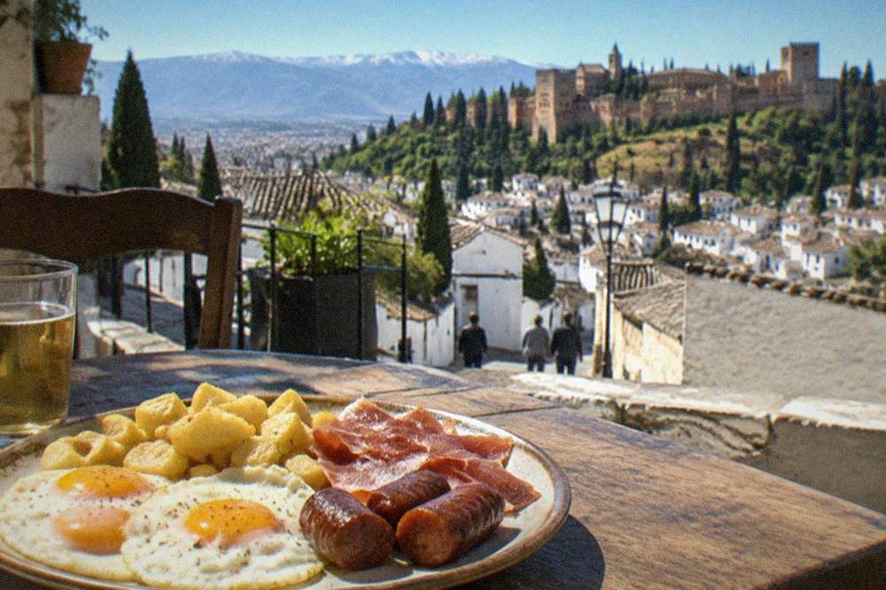 A plate of eggs, sausage, ham and potatoes served on a rustic table in a Granada bar