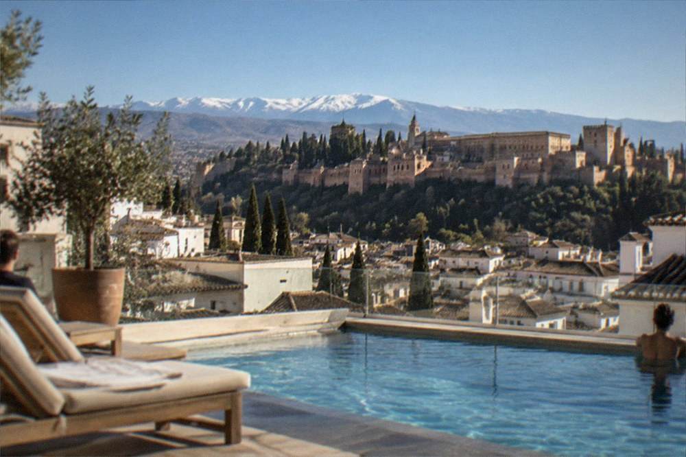 A hotel rooftop pool in Granada with the Alhambra visible in the distance