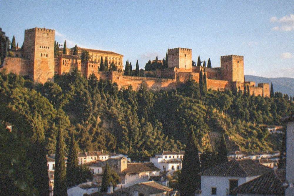 Granada rooftops at dusk with the illuminated Alhambra on the hill above the city