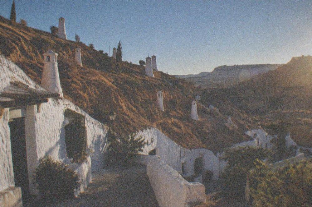 A whitewashed cave house street in Sacromonte lit up in the evening