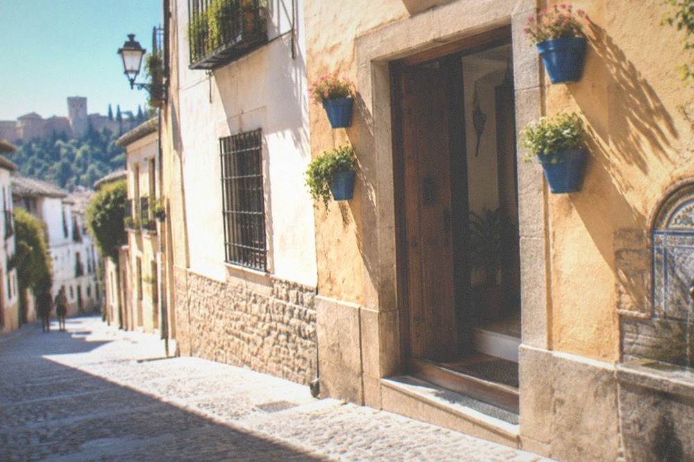 Guesthouse doorway with blue flower pots on a quiet Realejo street in Granada