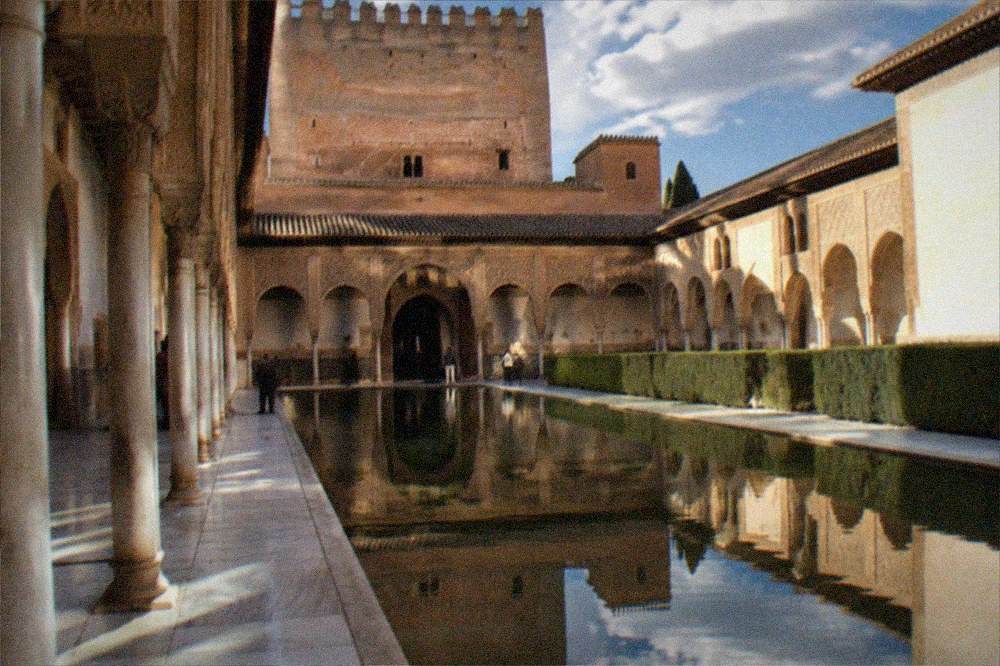 Nasrid Palaces courtyard arches reflected in a shallow pool at dusk
