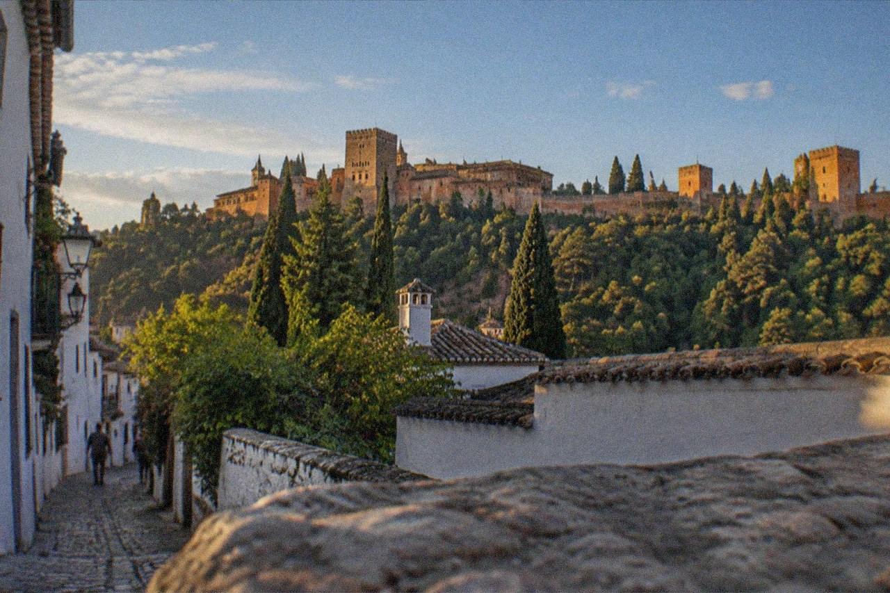 A quiet evening street in the Albaicin district of Granada with the illuminated Alhambra on the hill opposite