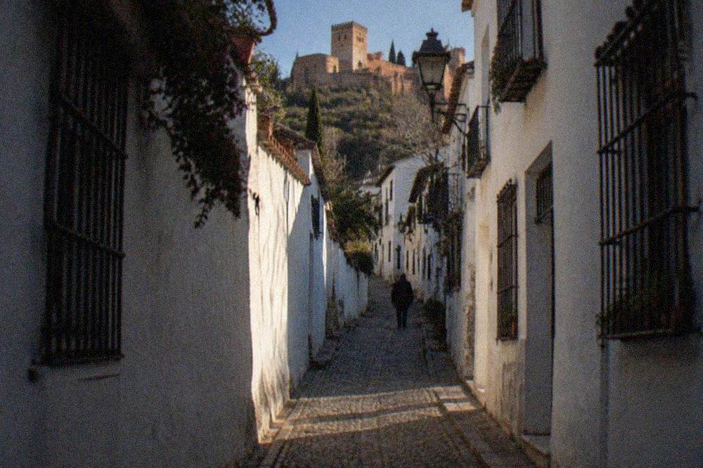 A dimly lit narrow cobbled lane climbing through the Albaicin quarter in the evening