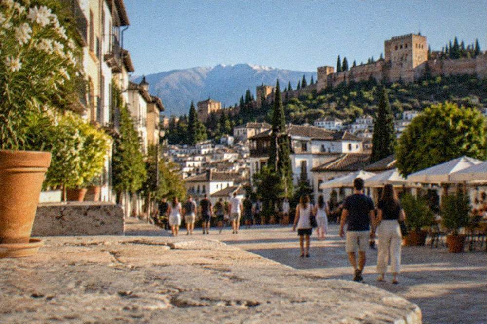 People strolling through a lit plaza in central Granada on a warm evening