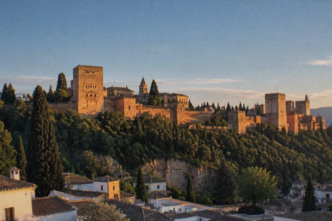 The Alhambra palace complex seen from a hillside viewpoint across Granada at golden hour
