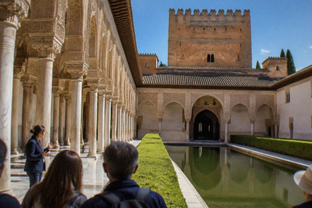 A guide speaking to a small group of visitors in the courtyards of the Nasrid Palaces