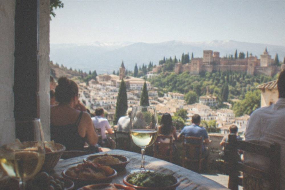 A table of small tapas plates and glasses of wine in a crowded traditional Granada bar