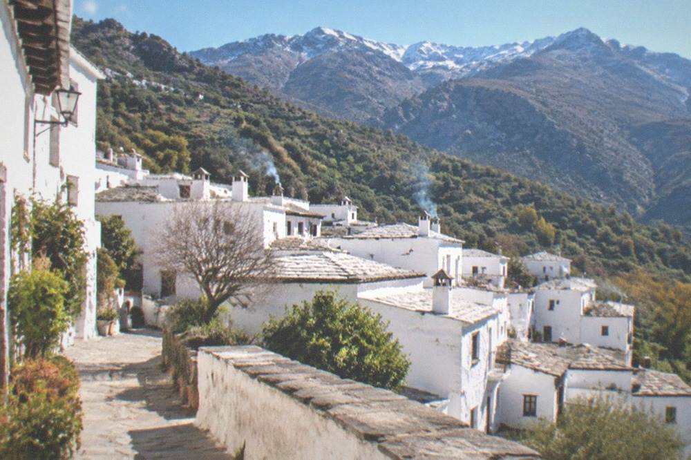 A whitewashed mountain village terrace in the Alpujarras with the Sierra Nevada behind