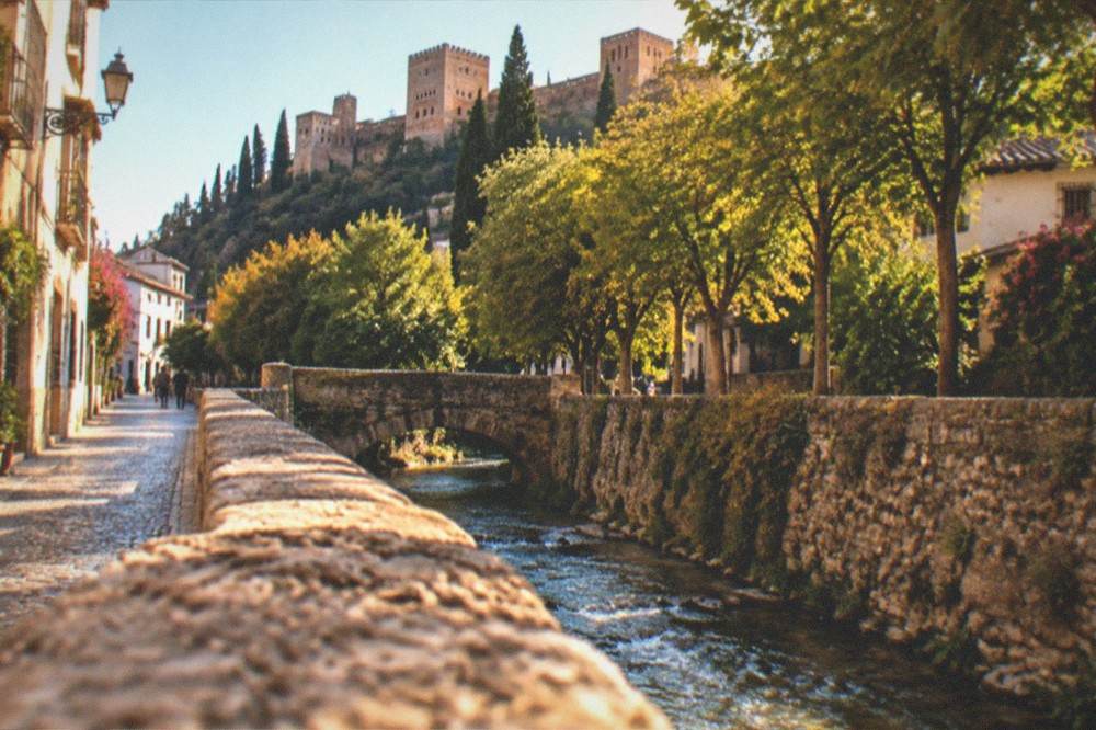 The tree-lined Carrera del Darro street along the river with the Alhambra walls above