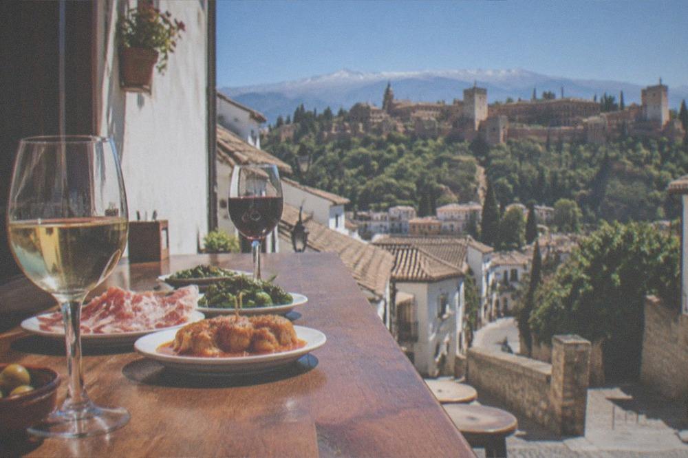 A small bar counter with glasses of wine and plates of tapas set out along the wood top