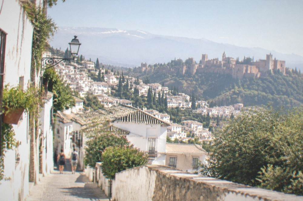 A mountain village of flat-roofed white houses terraced on a green hillside