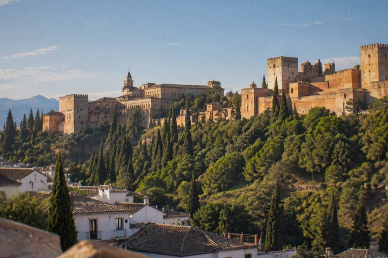 The Alhambra palace complex seen from a hillside viewpoint across Granada at golden hour