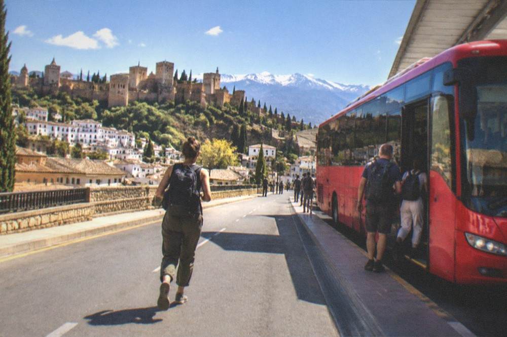 A red airport shuttle bus parked at a terminal kerb with passengers boarding