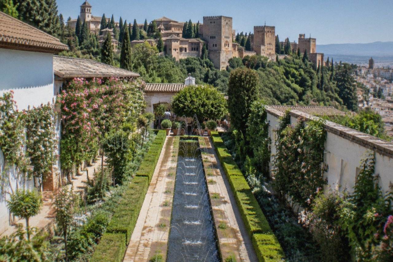 The Alhambra palaces and Generalife gardens seen from a hillside above Granada under a clear blue sky