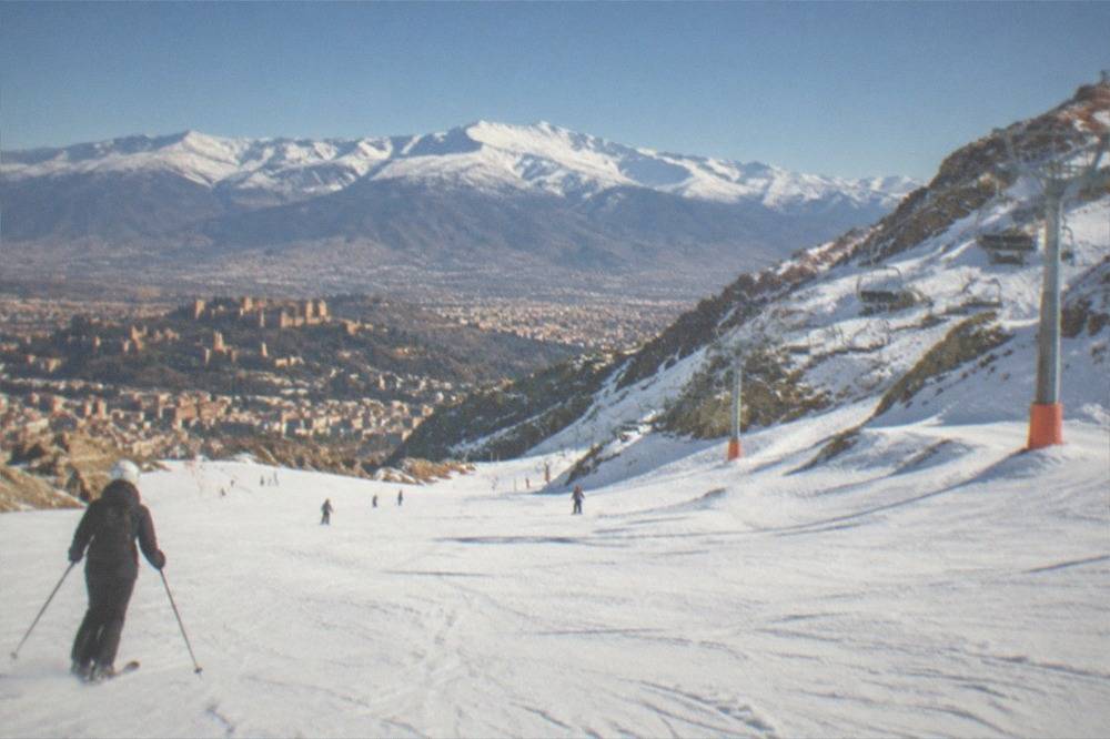 Snow-capped Sierra Nevada mountains rising behind the rooftops of Granada on a clear winter day