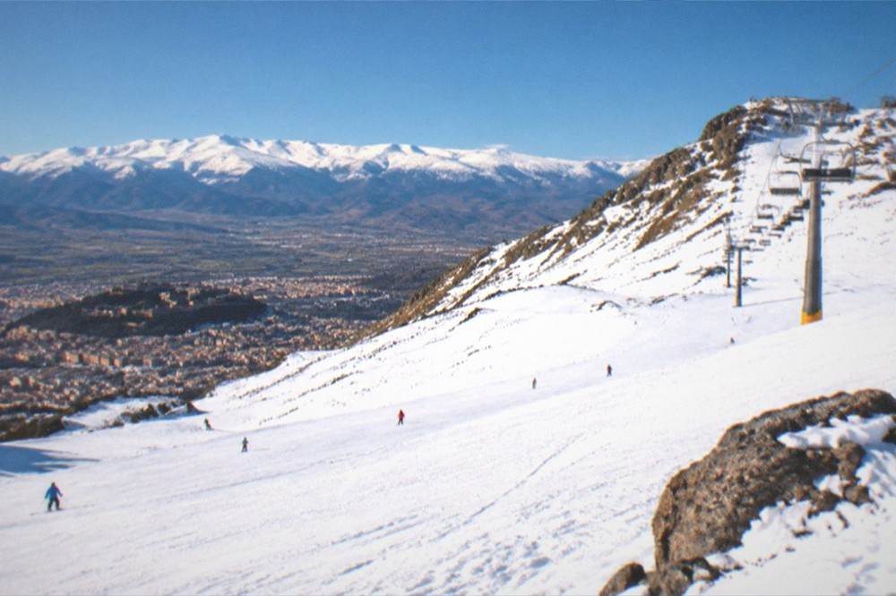 A wide view across Granada's rooftops with the Sierra Nevada glowing at sunset behind the city