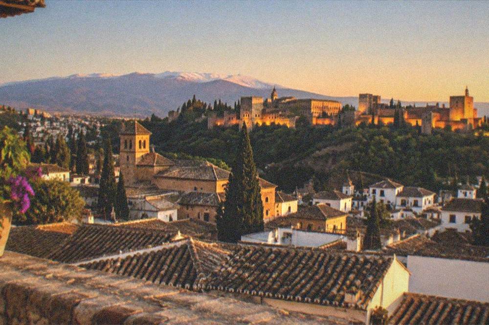 Evening view across Granada rooftops toward the illuminated Alhambra on its hill