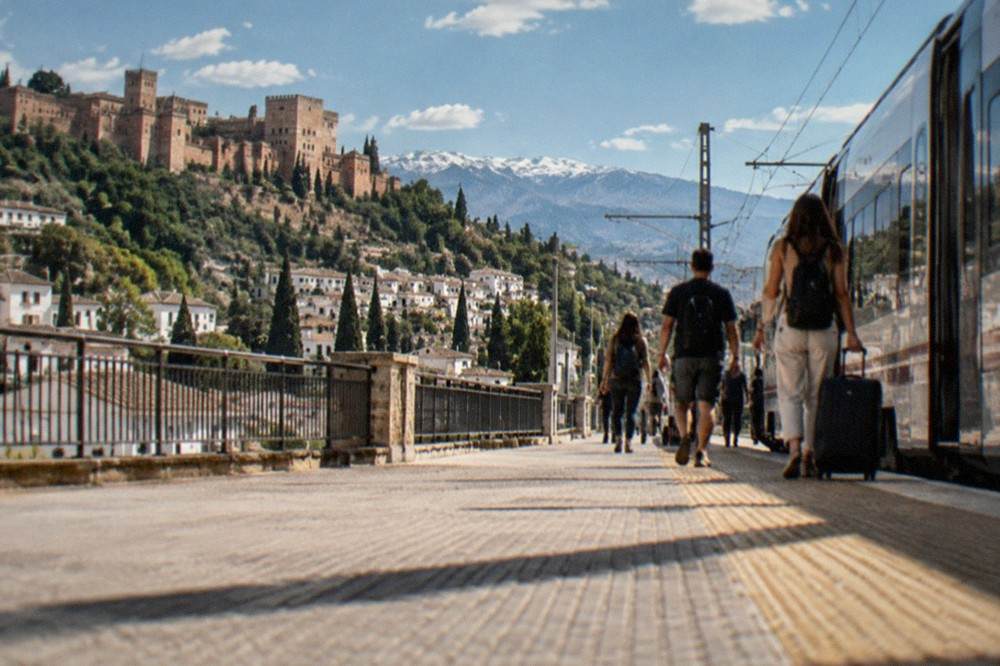 Passengers walking along a station platform toward a waiting train