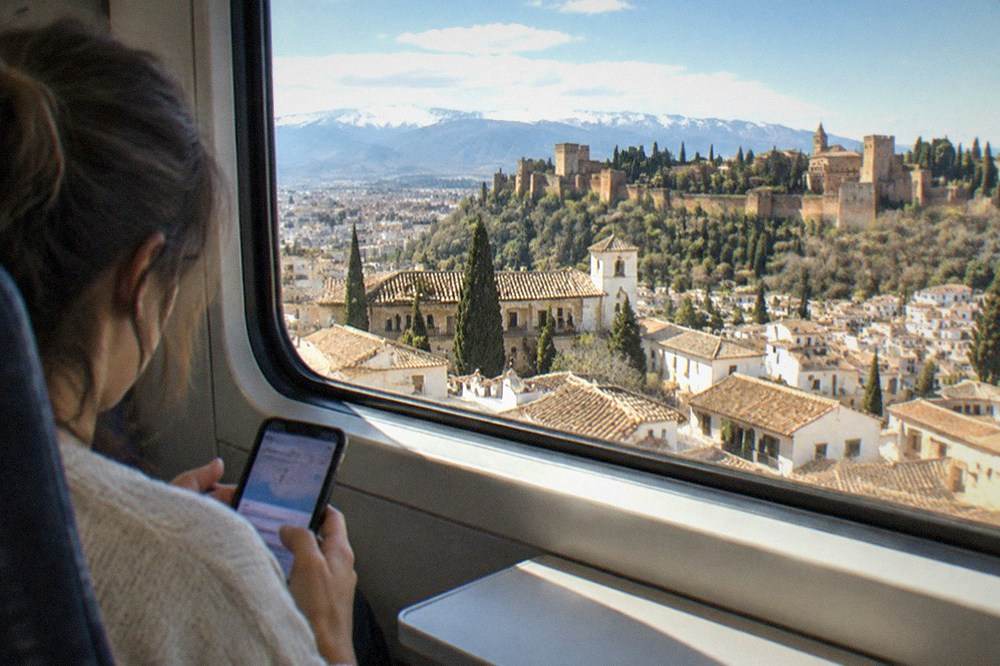 A traveler checking a ticket app on a phone inside a modern train carriage