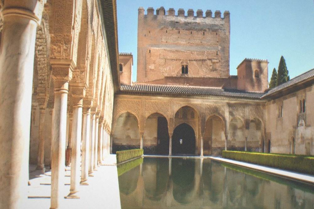 The courtyard of the Nasrid Palaces with ornate arches and a reflecting pool