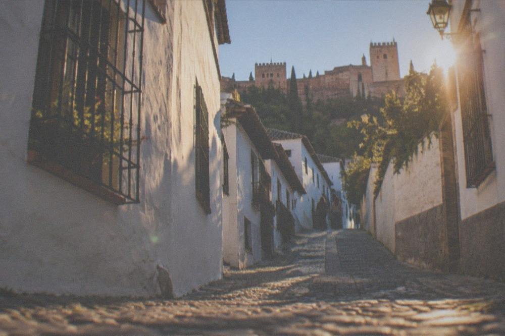 A narrow whitewashed street in the Albaicin quarter at golden hour
