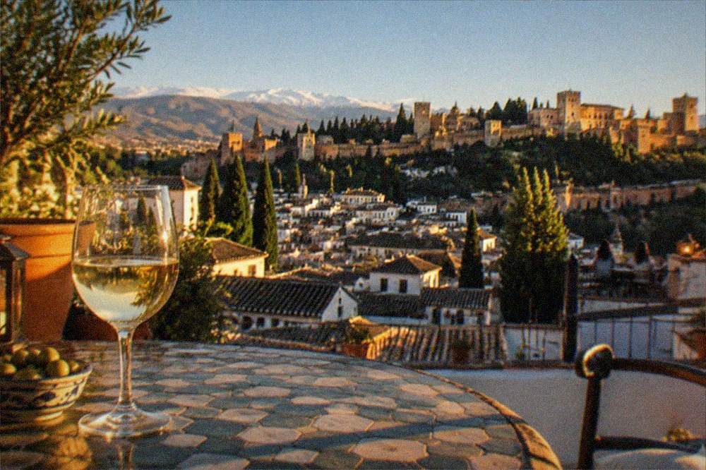 A hotel terrace overlooking lit-up city rooftops at night in Granada