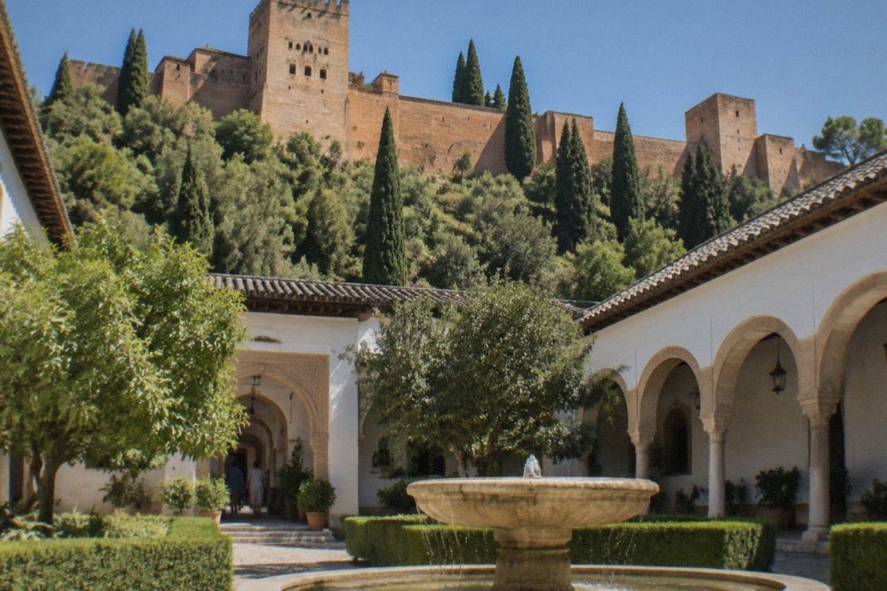 A hotel courtyard with stone arches and a fountain inside the Alhambra grounds in Granada