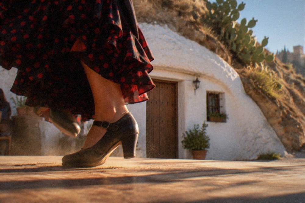 A close view of a flamenco dancer's feet striking a wooden cave floor, dust rising in the stage light