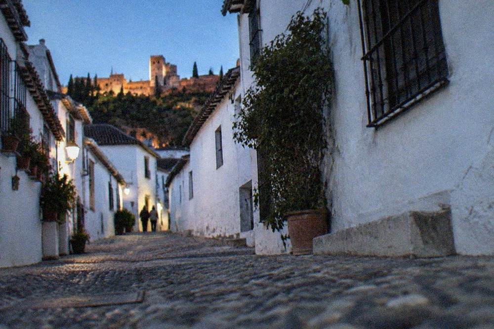 A narrow cobbled street with white houses in the Albaicin quarter of Granada