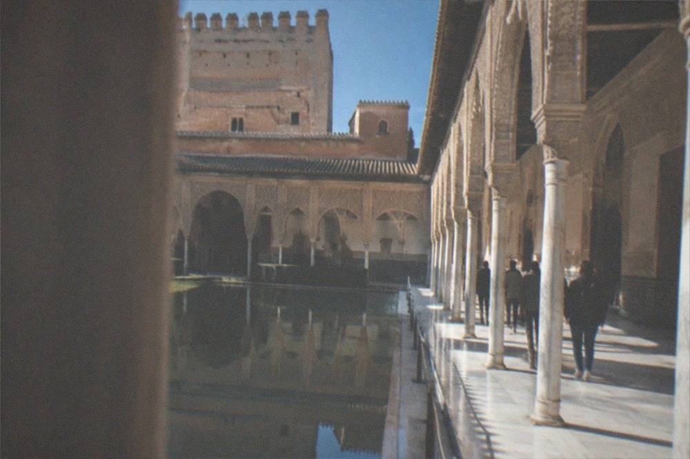 Visitors walking through the ornate arched courtyards of the Nasrid Palaces in the Alhambra