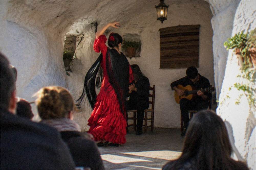 A flamenco dancer performing inside a whitewashed cave venue in Sacromonte
