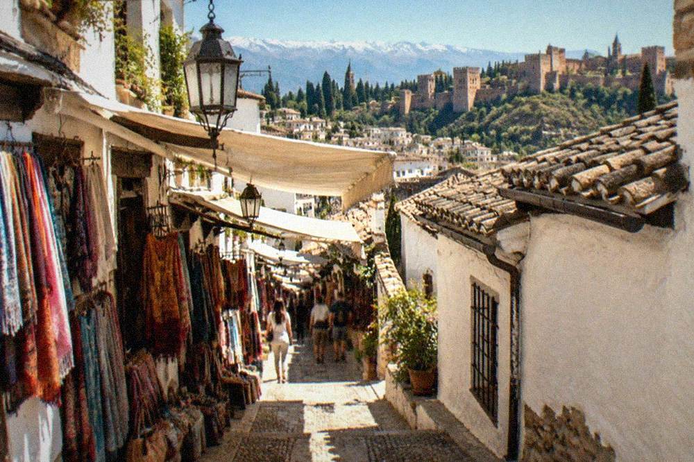 A covered market lane with hanging lanterns and colourful scarves in central Granada