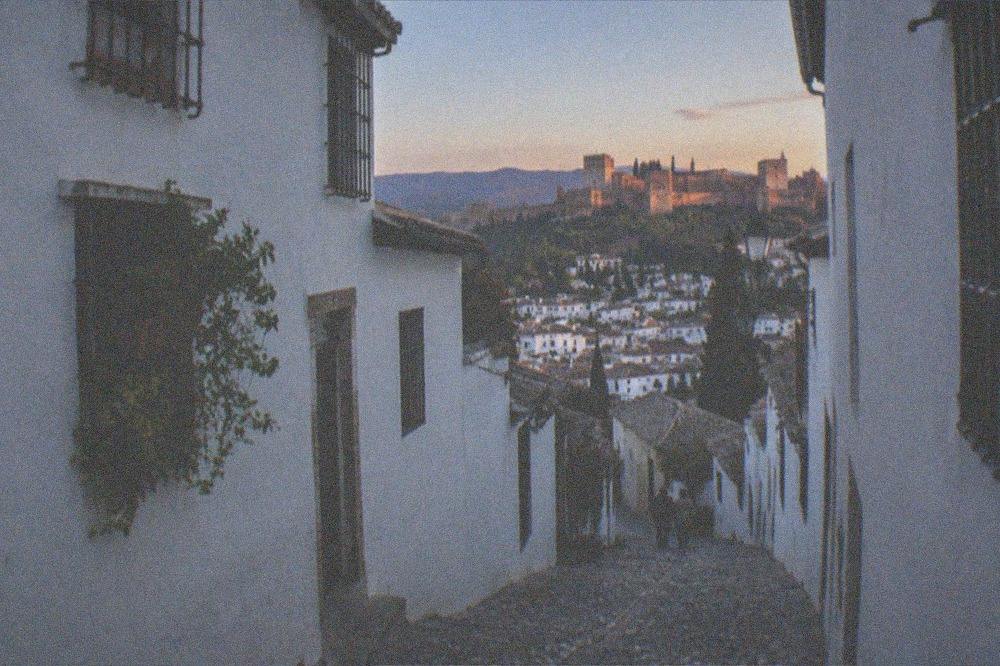 The white houses of the Albaicin seen across a valley toward the Alhambra at sunset