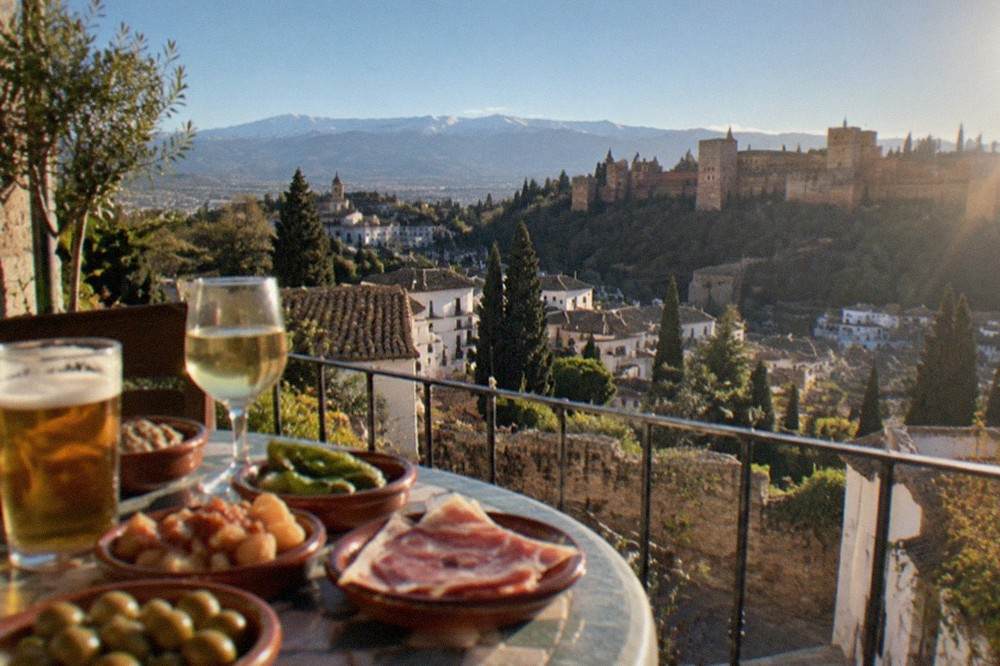 Small tapas plates brought to a table with drinks in a Granada bar