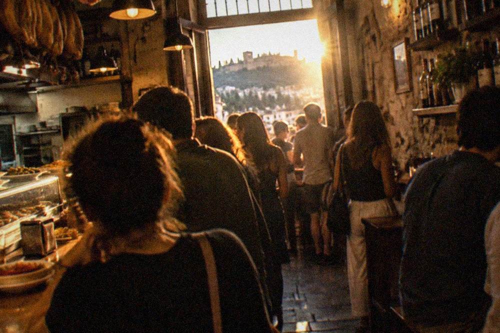 A narrow Granada tapas bar interior with a crowded counter at night