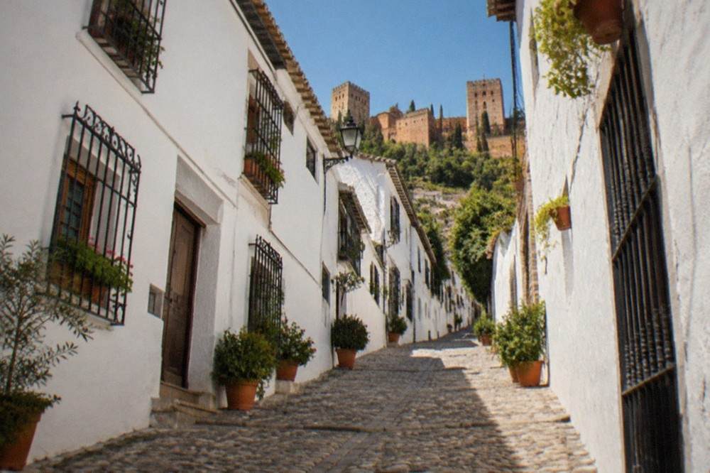 A narrow cobbled street in the Albaicin with whitewashed houses and potted plants