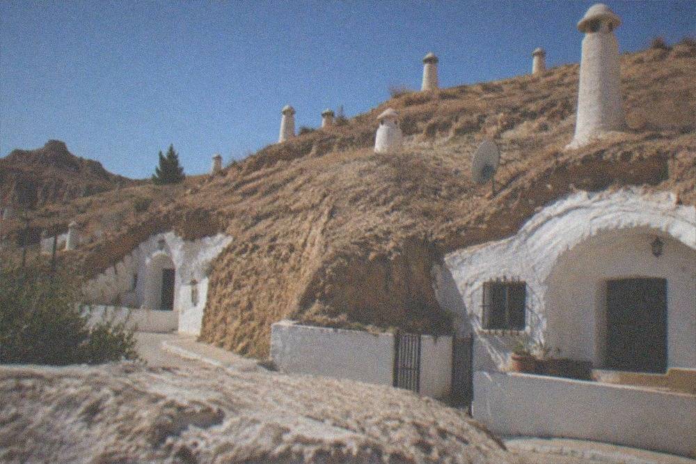 Cave house facades with white arches on the Camino del Sacromonte at dusk