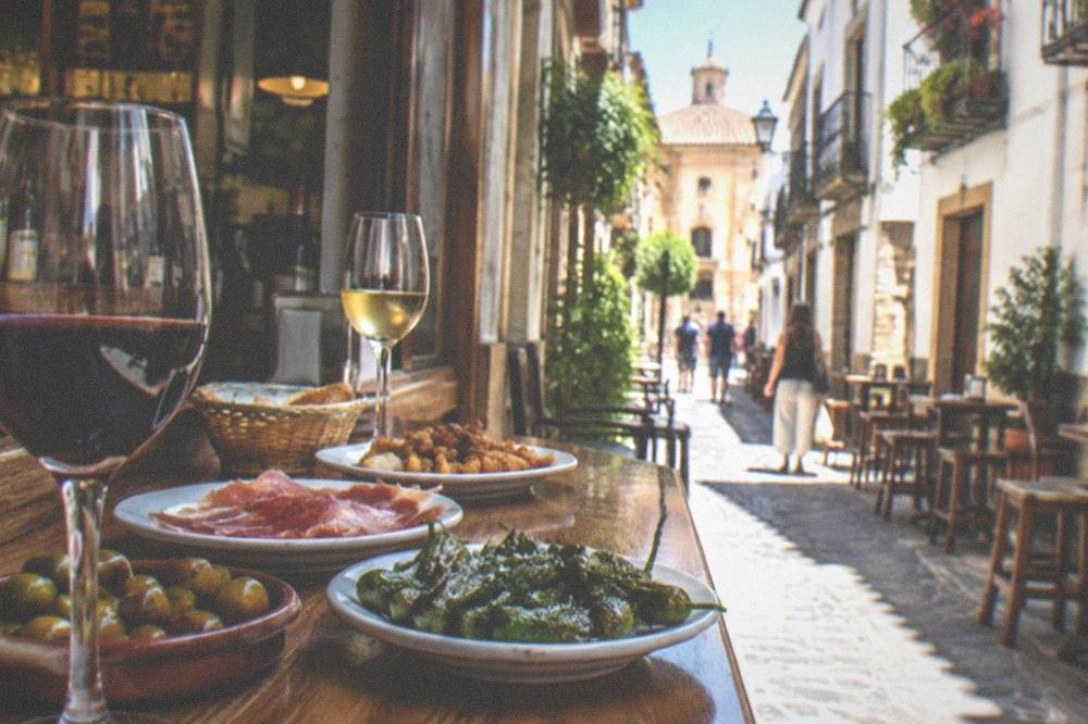 A lively tapas bar interior with plates of food and glasses of wine on a counter