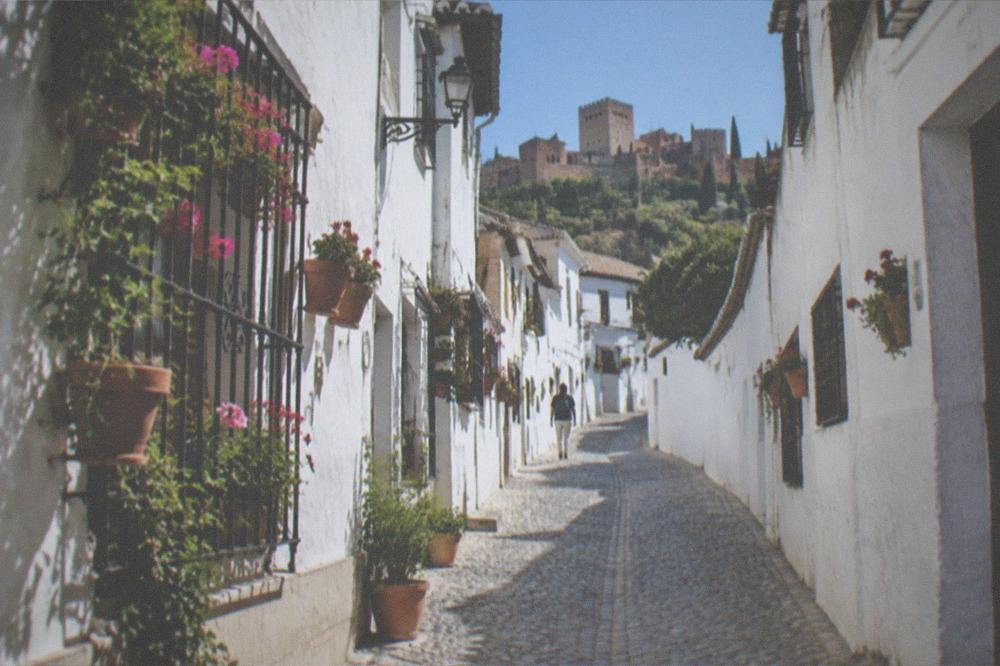 A narrow cobbled street in the Albaicin quarter with white houses and flower pots