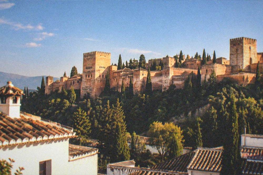 The Alhambra towers against an evening sky seen from a city rooftop