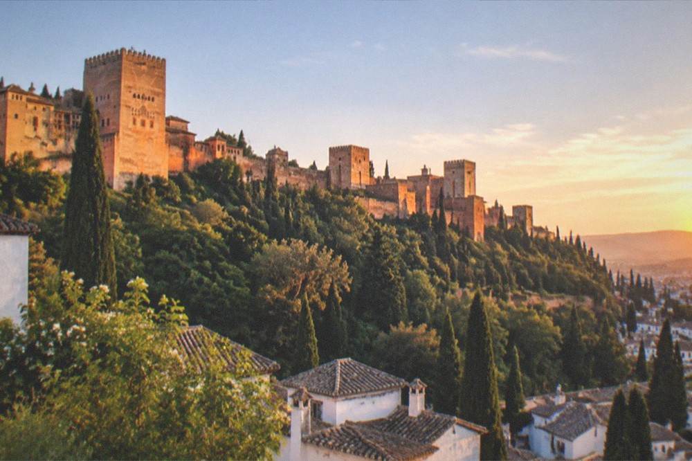 A sunset view over the Albaicin rooftops with the Alhambra glowing on the opposite hill