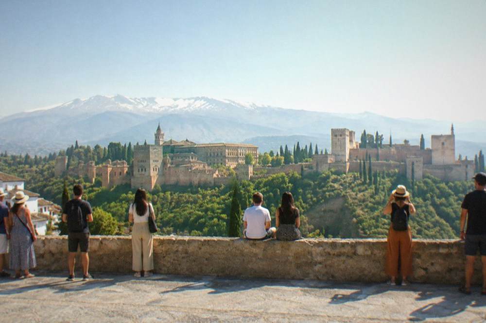 The Mirador de San Nicolas viewpoint crowded with visitors looking across at the Alhambra at sunset