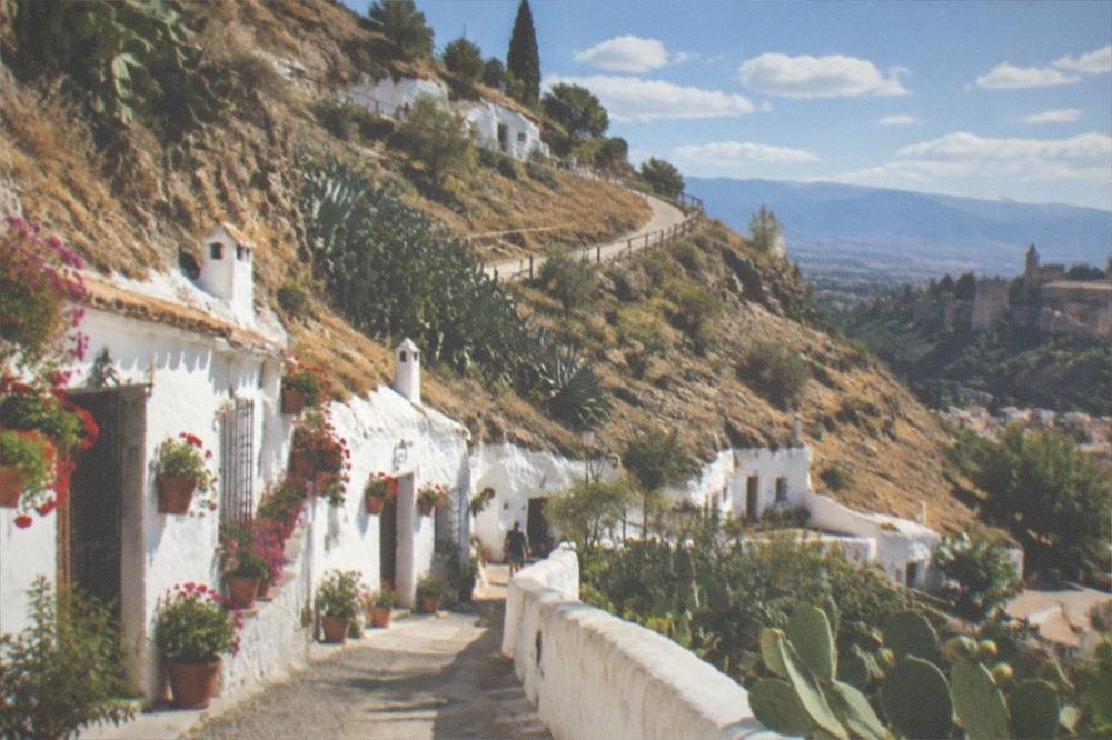 White cave-house facades with flower pots along a lane in Sacromonte above Granada
