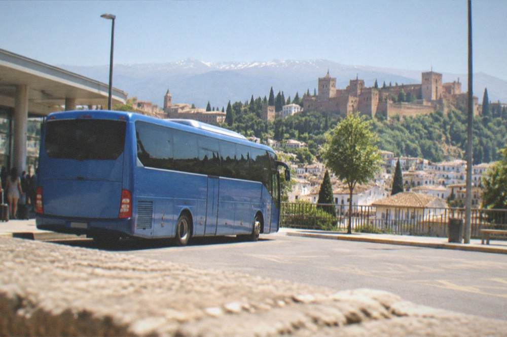 An Alsa airport bus parked at a stop outside Granada Airport terminal