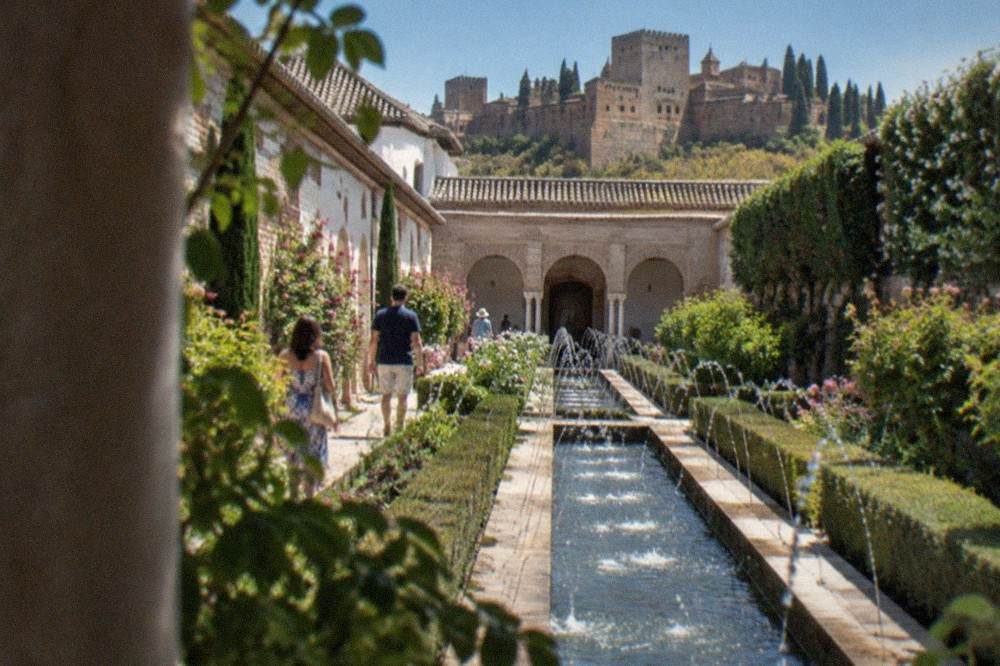 Visitors walking through the arched courtyards of the Generalife gardens above Granada