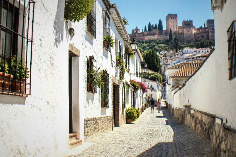 The white houses of the Albaicin quarter climbing a hillside above red rooftops