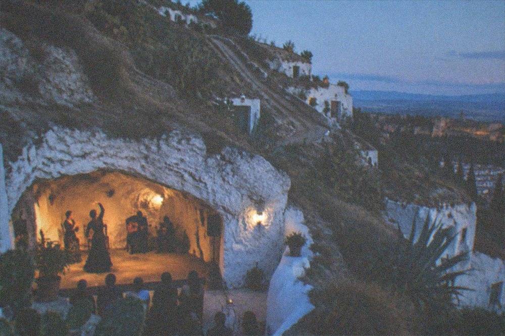 A cave flamenco performance with dancers and guitar inside a whitewashed Sacromonte cave