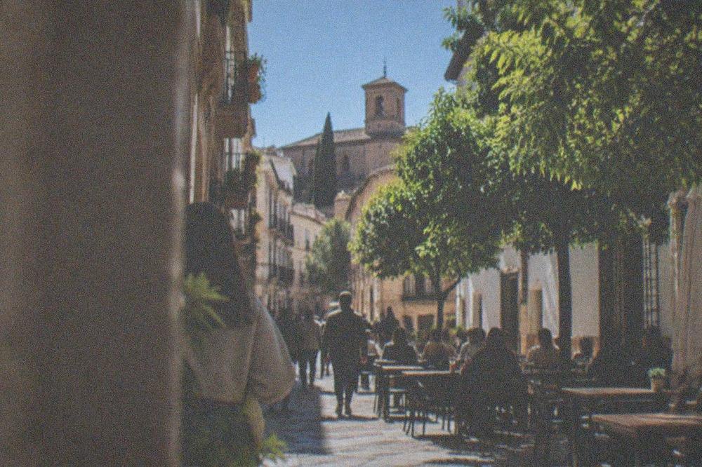 An evening plaza in Granada old town with cafe tables under lit trees